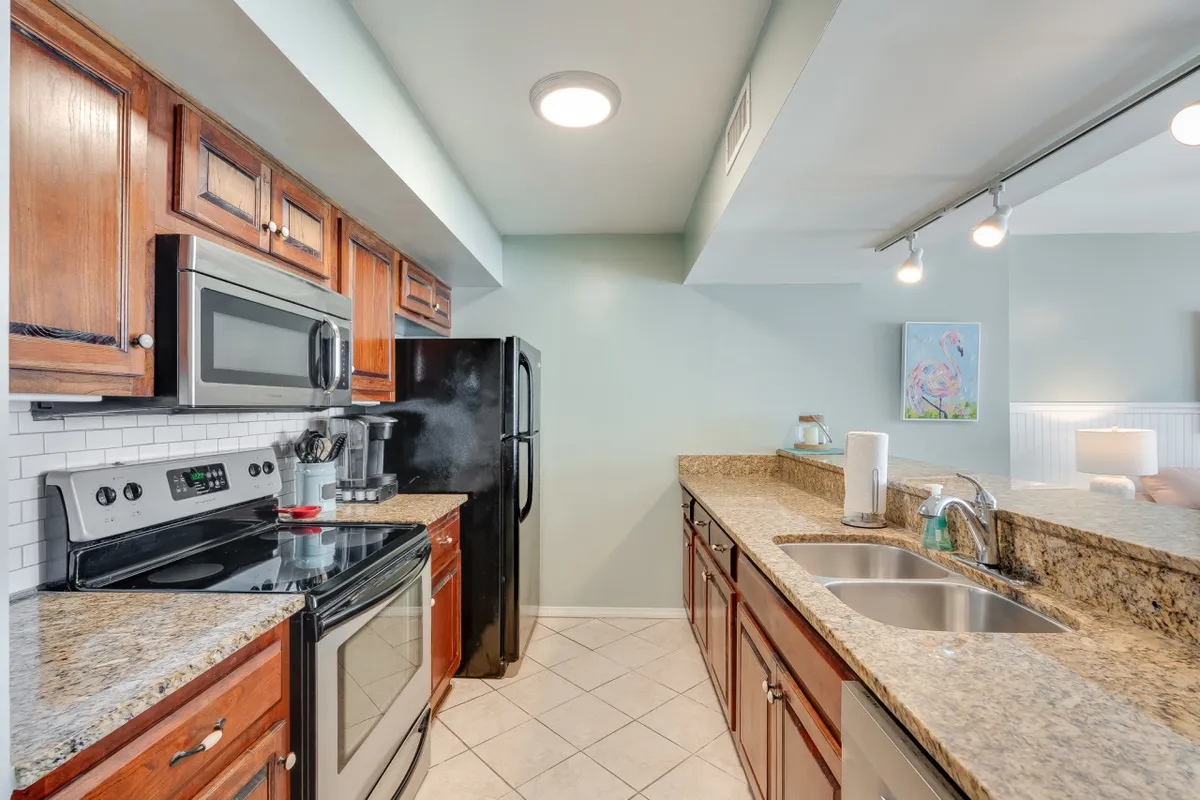 A modern kitchen featuring granite countertops, sleek stainless steel appliances, and rich wood cabinetry. The sink area is clean and well-lit, with inviting details that suggest a space designed for both cooking and entertaining.